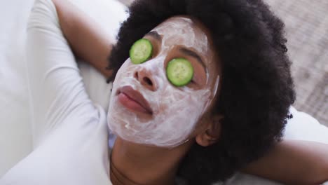 Close-up-of-african-american-woman-wearing-face-mask-laying-on-the-bed