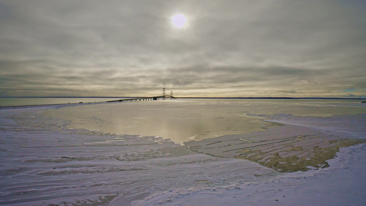 Mackinac Köprüsü'nün donmuş buz oluşumları ve önünde taze karla çekilmiş manzaralı drone görüntüleri.
