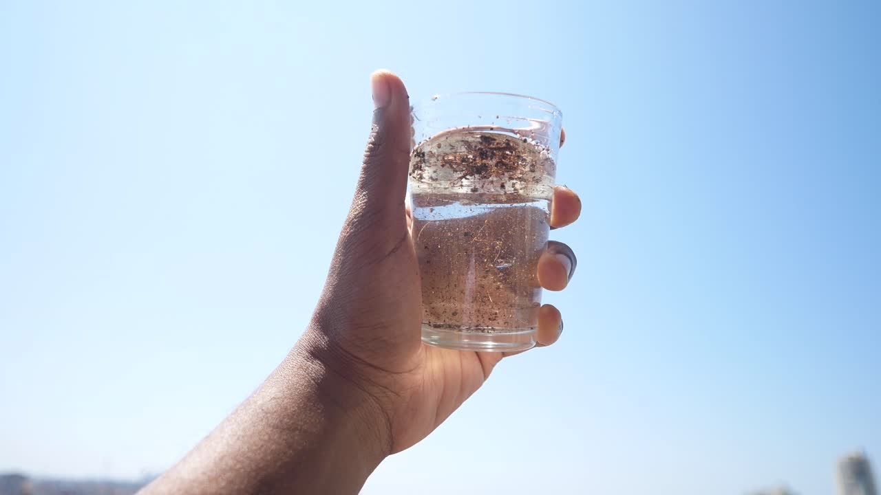 mano sosteniendo un vaso de agua sucia