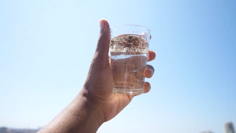 mano sosteniendo un vaso de agua sucia