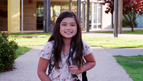 Una-Colegiala-De-Raza-Mixta-Caminando-Hacia-La-Cámara-Sonriendo,-Al-Aire-Libre