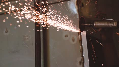 Using-an-angle-grinder-with-sparks-flying-while-cutting-metal,-close-up-of-grinding-and-manufacturing-aluminium