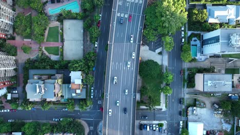 上下跟踪繁忙的道路的空中视图,有很多汽车,树木和房子可见