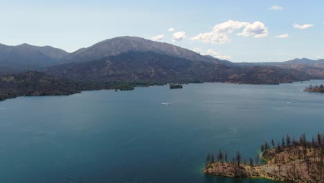 Panorama-Luftdrohnenaufnahmen-Eines-Blauen-Sees,-Umgeben-Von-Pinienbergen