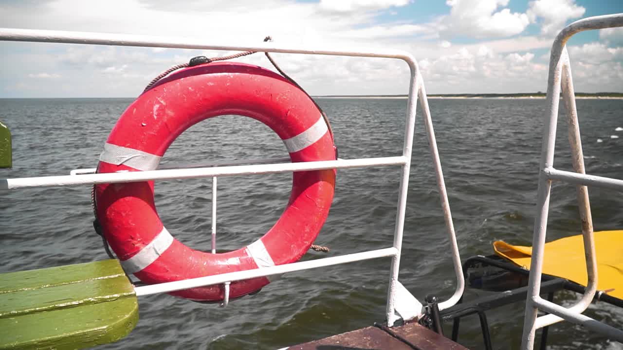 보트 울타리에 있는 빨간 구명부표의 총, 물결치는 바다