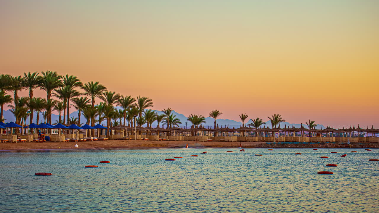 Timelapse di una spiaggia desertica con palme e amache al tramonto, che mostra colori dorati