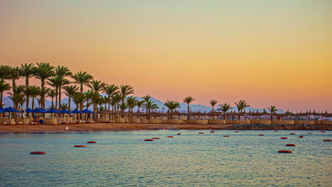 Timelapse-De-Una-Playa-Desierta-Con-Palmeras-Y-Hamacas-Al-Atardecer,-Mostrando-Colores-Dorados