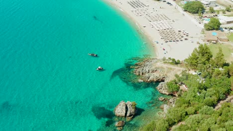 Vista-De-Arriba-Hacia-Abajo-De-Las-Pintorescas-Aguas-De-La-Playa-De-Karavostasi,-Inclinación-Hacia-Arriba-Que-Revela-El-Exclusivo-Hotel-Elix-Mar-Bella,-Grecia