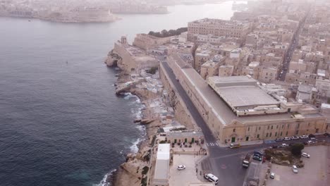 High-Altitude-drone-flight-from-over-the-Ocean-to-the-left-with-waves-and-mighty-walls-in-Valletta-Malta