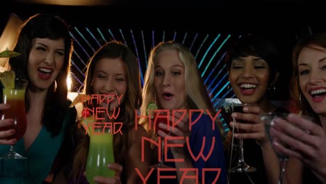 Animation-of-happy-new-year-text-in-red-over-diverse-group-of-happy-women-drinking-cocktails-in-bar