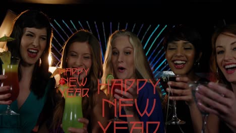 animation of happy new year text in red over diverse group of happy women drinking cocktails in bar