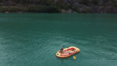 dando vueltas alrededor de una chica remando un pequeño bote de goma en un lago verde