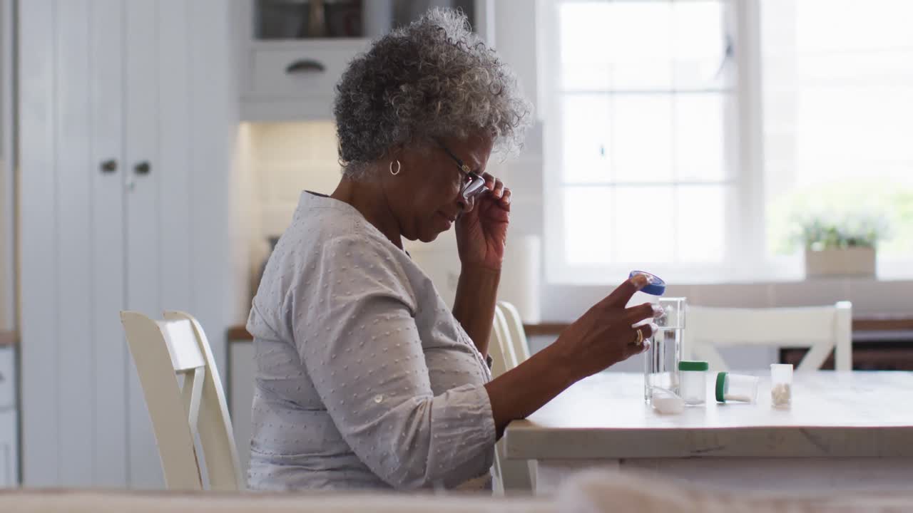 Senior african american woman looking at empty medication container while sitting at home