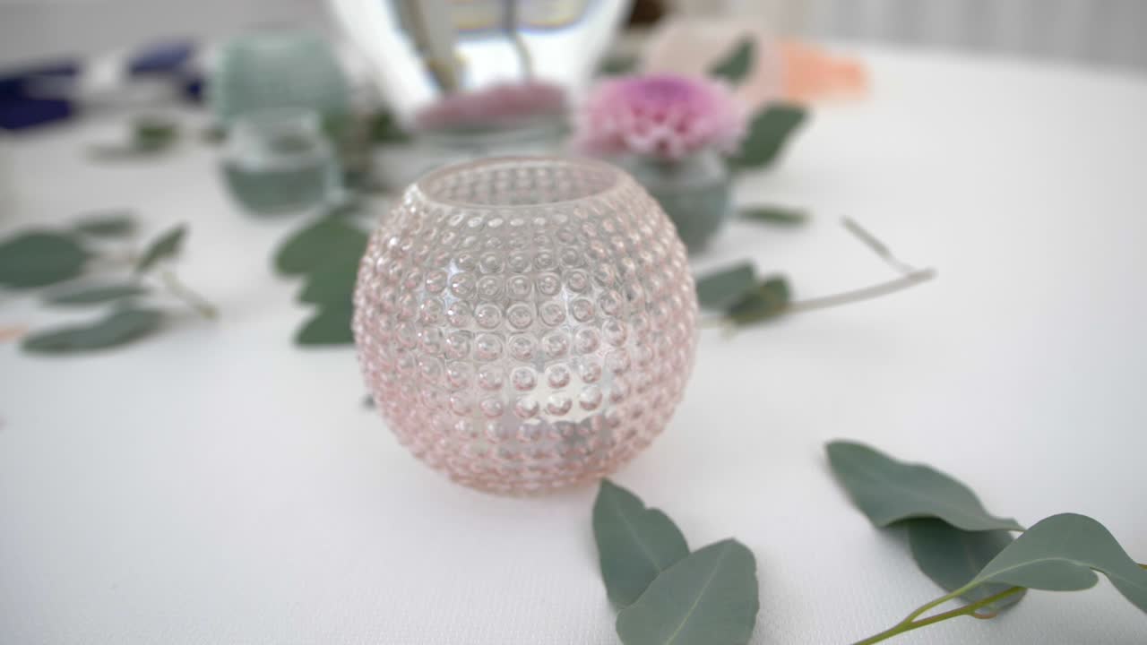 웨딩 장식, 유칼립투스 잎이 있는 흰색 테이블에 촛불이 있는 아름다운 분홍색 병