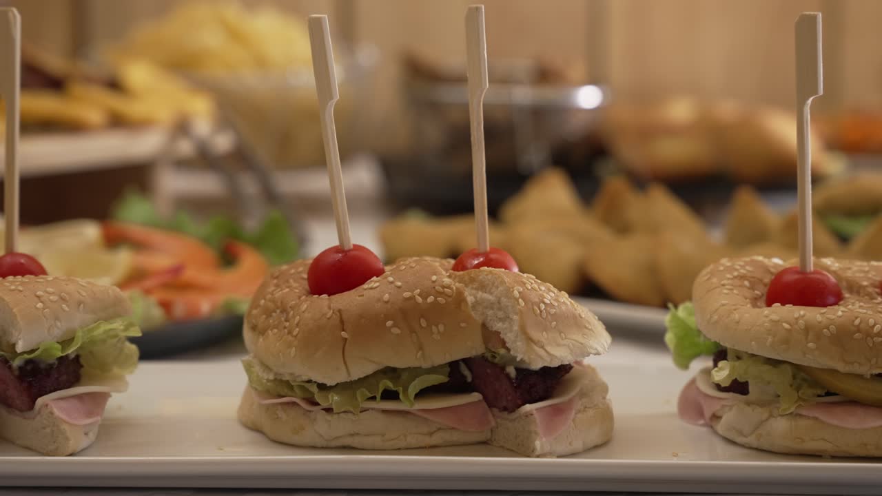 Tasty mini sandwiches skewered with cherry tomatoes on buffet table display