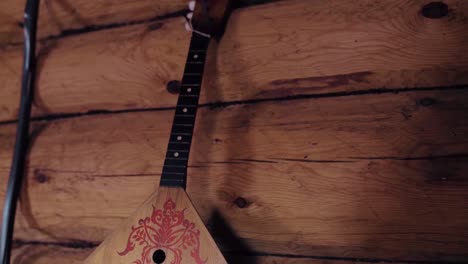 wooden balalaika hanging on log cabin wall