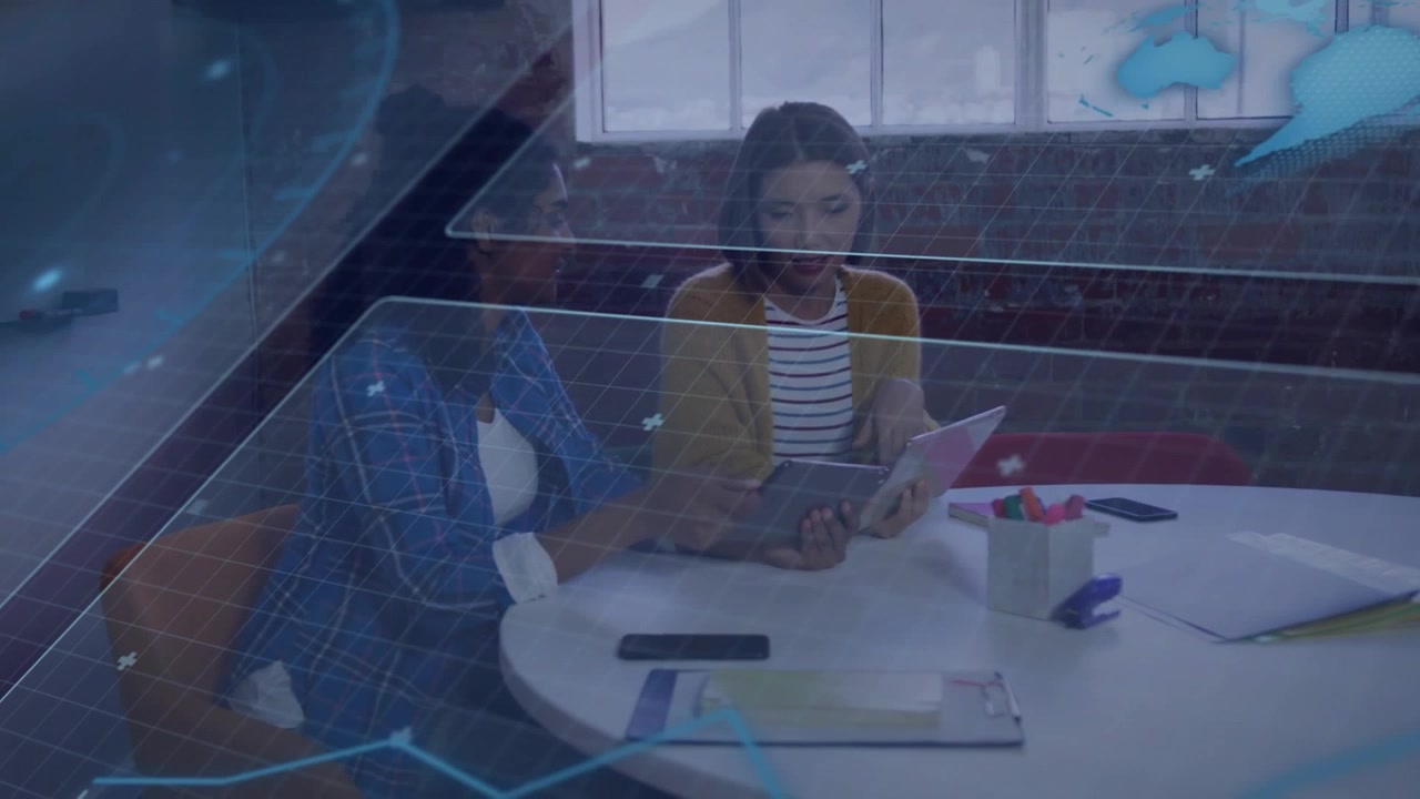 Two women sitting at business table, left woman leaning tapping tablet, initiating globe animating