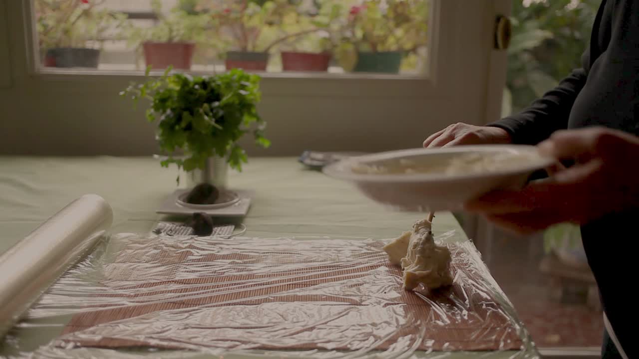 작물 요리사 는 실내 에서 요리 하는 동안 음식 포장 에 부드러운 치즈 를 넣고 있다