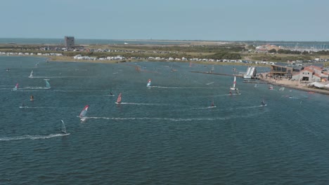 drone - aerial shot of many surfers on a blue, wavy and windy sea on a sunny day with white clouds on a island, 30p