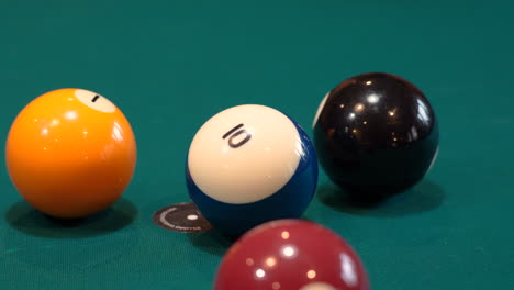 person breaks pool balls on 8 ball triangle rack closeup on the spot with solid and stripped billiard balls scattering on table with blue felt or cloth and 8 ball in frame