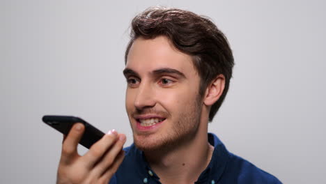 hombre sonriente grabando un mensaje de voz en un teléfono inteligente. hombre feliz usando un teléfono móvil