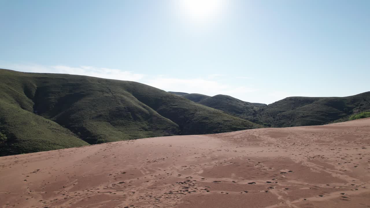 무인기 는 모래 언덕 위 에 물러나서 은 건조 한 풍경 을 가로질러 발걸음 을 습니다.