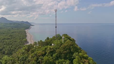 Cell-Towers-and-Lighthouse,-Surigao-Del-Norte-Besides-a-Beach-with-Sea-Visible-in-the-Background