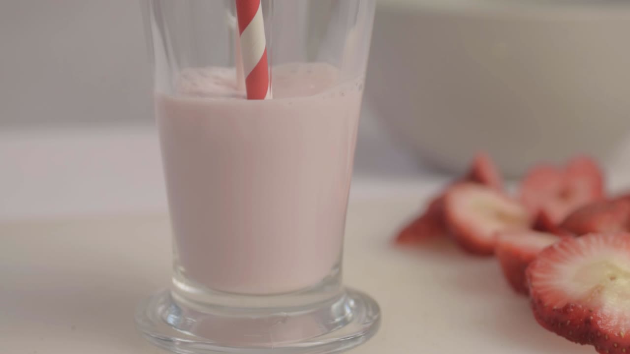 Primer plano de leche malteada de fresa vertiéndose en un vaso