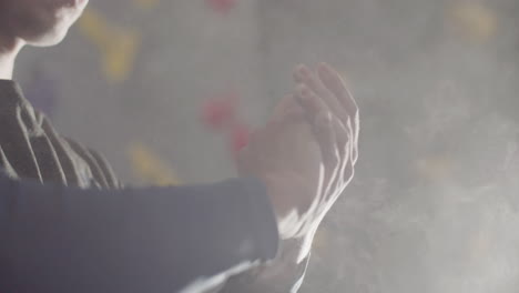 실내 볼더링 체육관에서 등반하기 전에 흰색 분필 가루로 덮인 손을 박수치고 문지르는 인식할 수 없는 스포츠맨의 클로즈업 샷