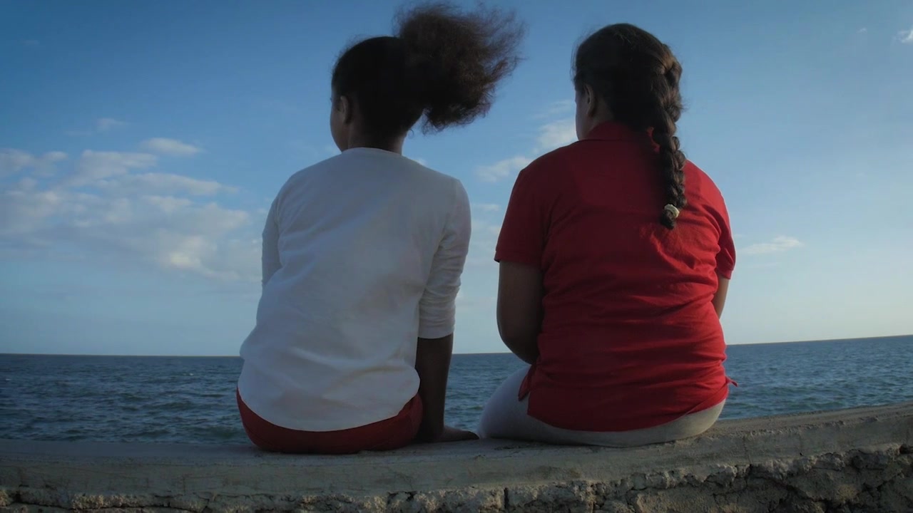 Sisters having fun waterfront, paralax right