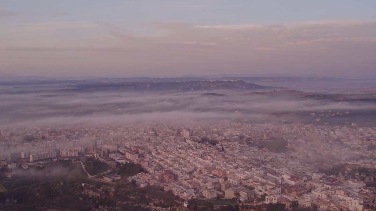 Sfumature tenui dell'alba avvolgono la città tranquilla sotto nuvole sparse