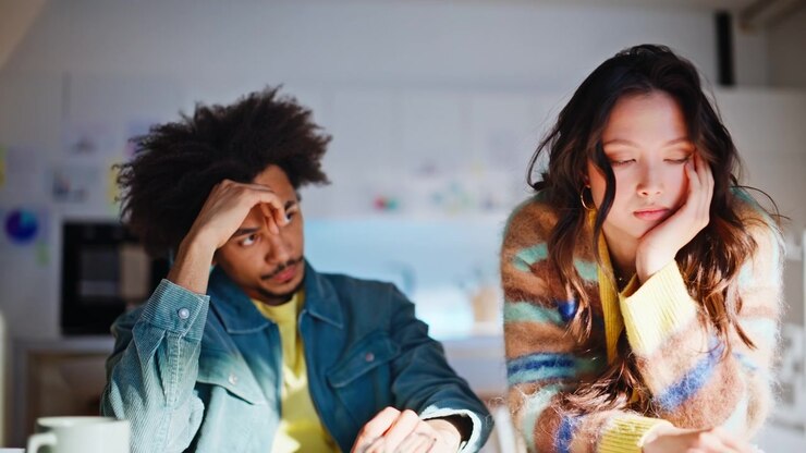 Multiracial couple upset bad news laptop kitchen. Startup failure sad exhausted