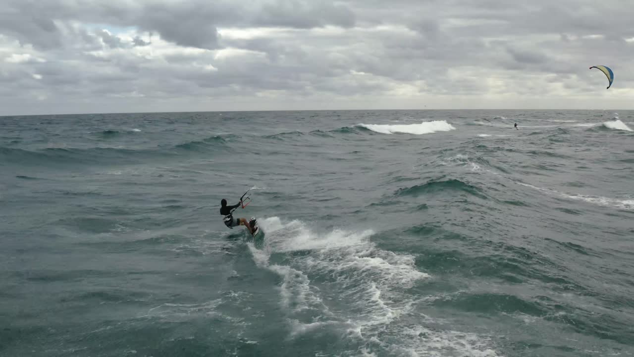 파도에서 큰 묘기를 부리는 카이트보더의 공중 비디오를 닫습니다.