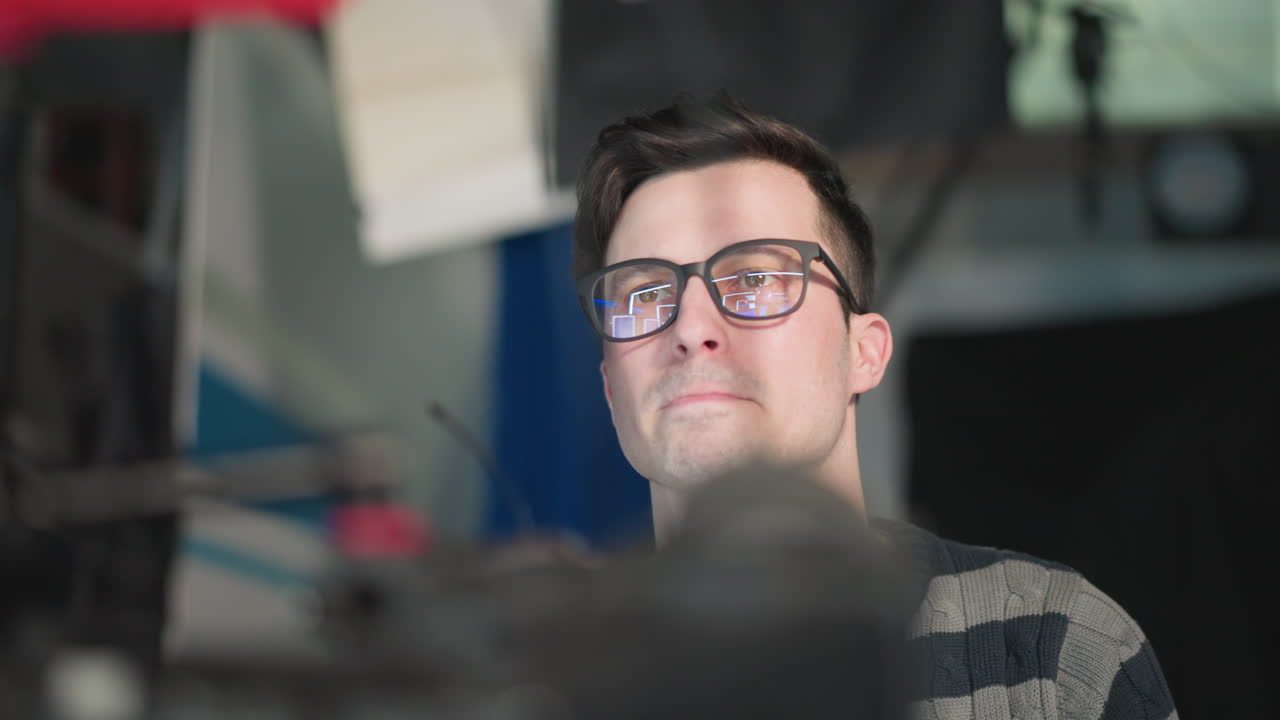 Close-up of camera operator adjusting broadcast camera in studio. Focused expression while preparing for filming, showcasing detailed view of camera setup with lights and equipment