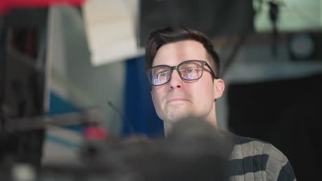 close-up of camera operator adjusting broadcast camera in studio. focused expression while preparing for filming, showcasing detailed view of camera setup with lights and equipment