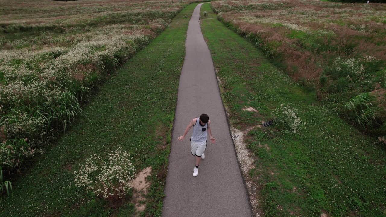Aerial drone view, man dancing down the trail in grassland
