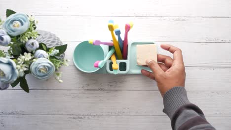 person placing soap in a bathroom toothbrush holder