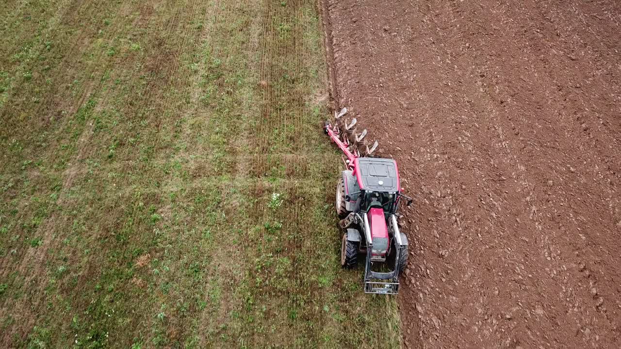 un tractor arando campos, retroceso aéreo lento de cerca a ancho