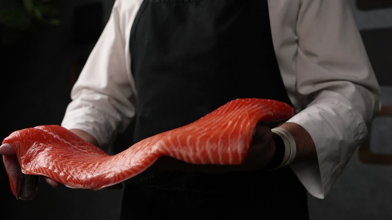 셰프가 생 살몬 한 조각을 들고 있다