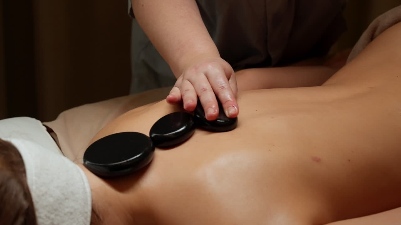 Nærbillede af hot stone massage på en kvindes ryg