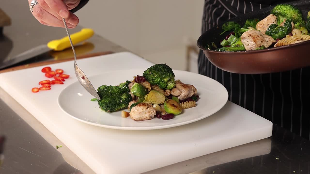 Chef che prepara un salutare piatto di pasta con pollo e verdure