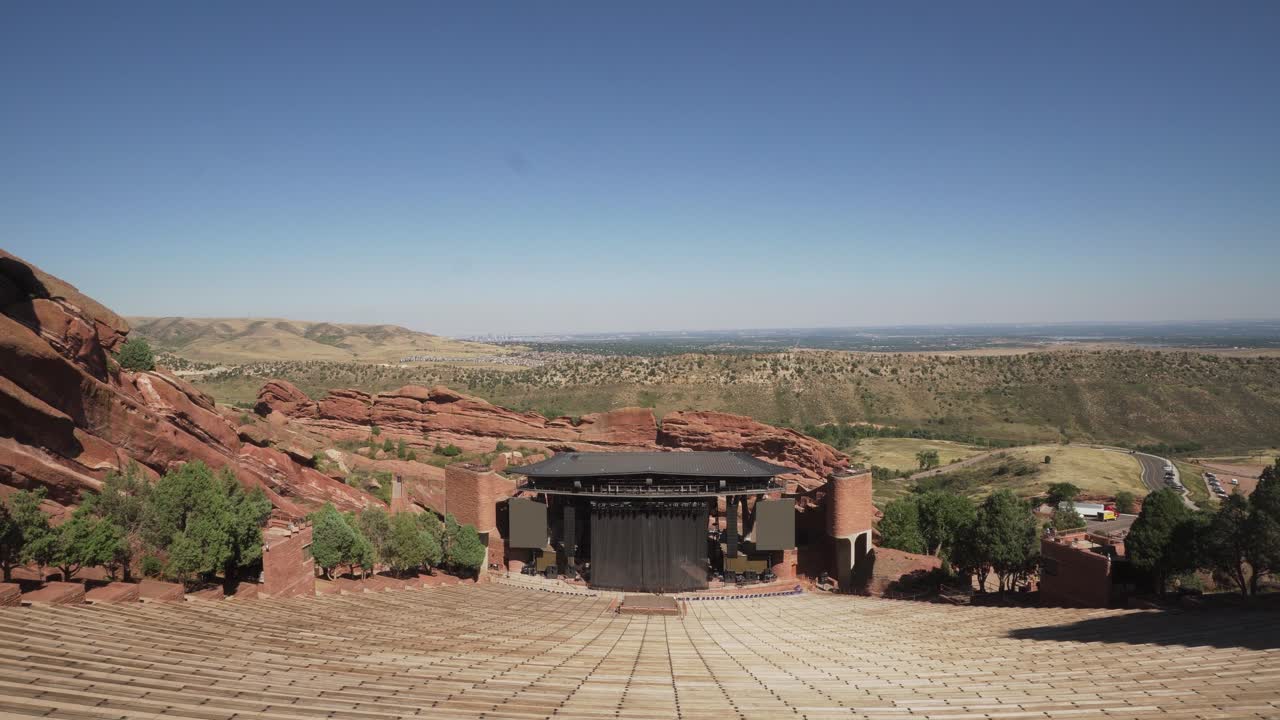 Red Rocks Amphitheater being prepared for a concert, overlooking Denver, daytime. Pan Down to Seats