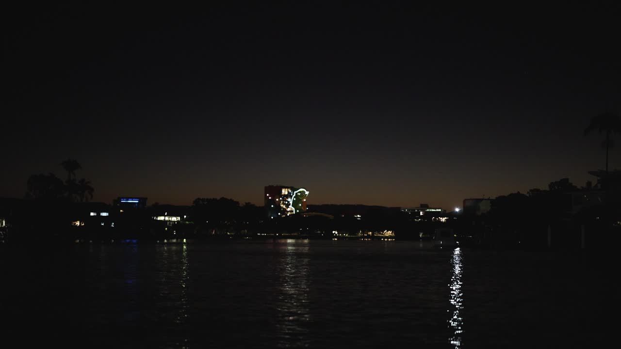 освещенная береговая линия отражается на спокойной воде ночью