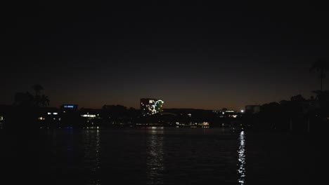 línea de costa iluminada reflejada en el agua tranquila por la noche