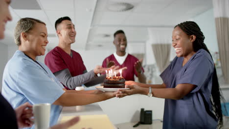 diverse male and female doctors celebrating birthday at reception desk at hospital, slow motion