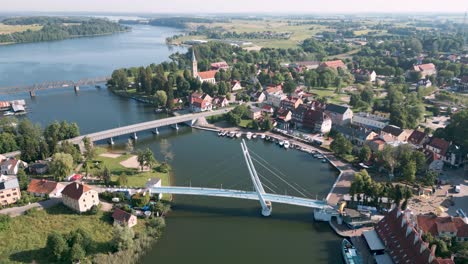 mikolajki, poland - descend aerial bird drone view flight over the pedestrian bridge most wiszacy of the touristic city in warmian masurian with blue sea and tiny ships and yachts in summer 2022