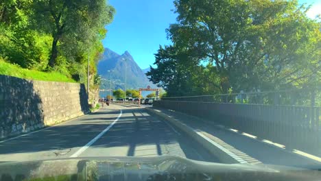 car point of view on mountain road with alpine lake lugano in a sunny day