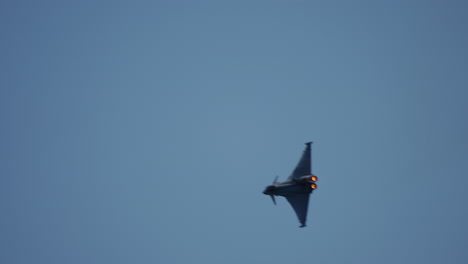 military jet fighter banking in sky with visible afterburners filmed in slow motion