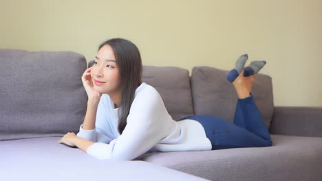 예쁜 젊은 여성이 소파에 누워 발을 차며 꿈을 꾸고 있다