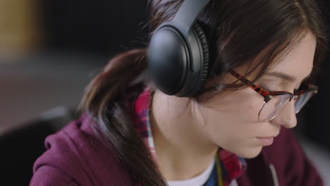 close-up-young-caucasian-woman-student-using-laptop-computer-typing-online-email-messages-working-on-project-listening-to-music-in-office